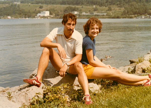 David and Sarah sit on rock by a lake.