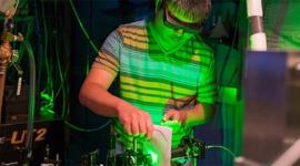 student working on green laser in dark lab room