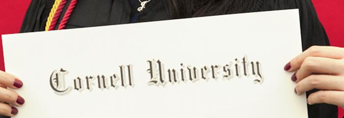 photo of a student holding their diploma with the Cornell University title 