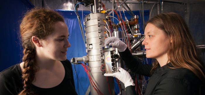 Professor Lena Kourkoutis (right) perpares to load electron transport samples into a dedicated scanning transmission electron microscope for atomic-scale imaging and spectroscopy.