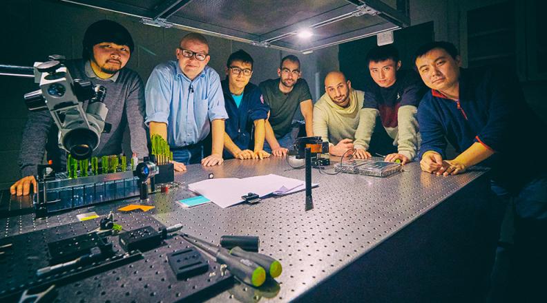 mcmahon and lab members around a laser 